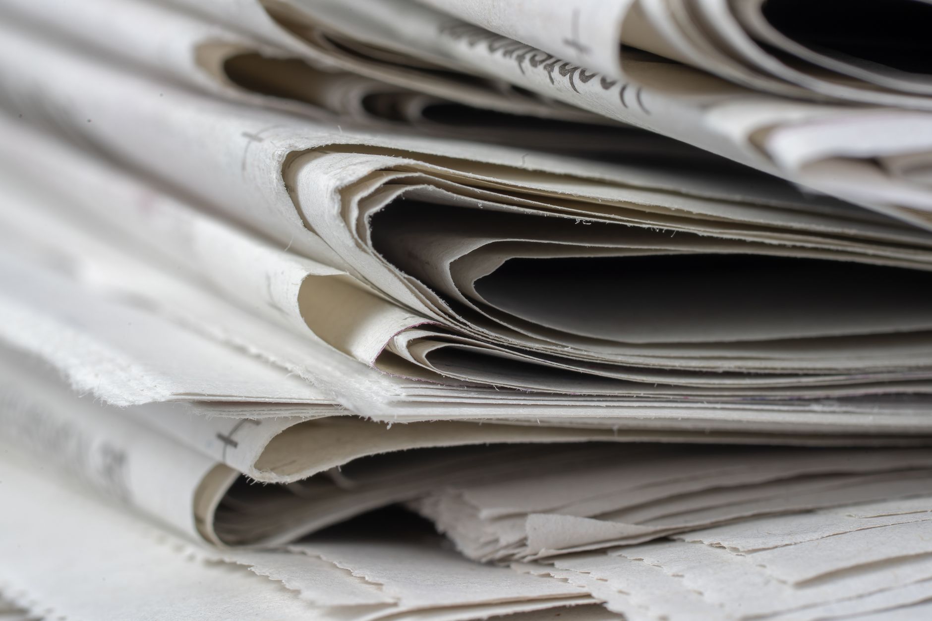 Close-up view of stacked, folded newspapers showing their edges and layers.